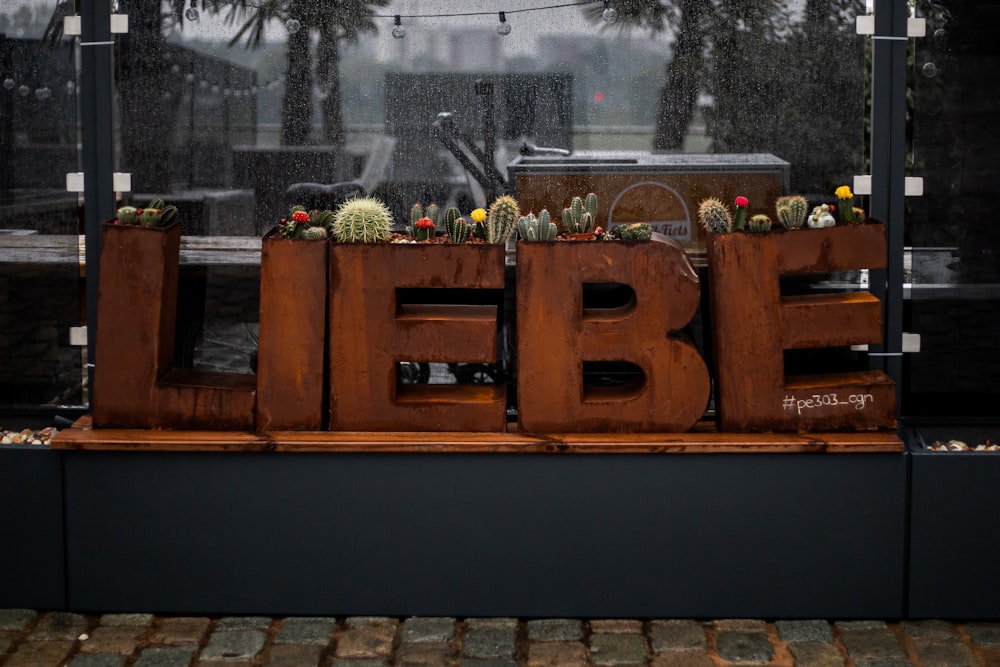 a wooden sign with plants in it on a sidewalk