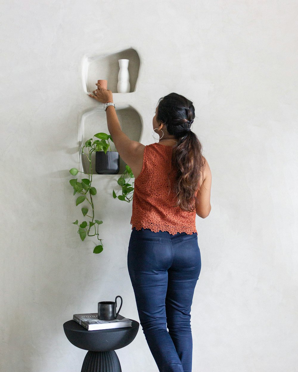 uma mulher colocando uma planta em um vaso em uma parede