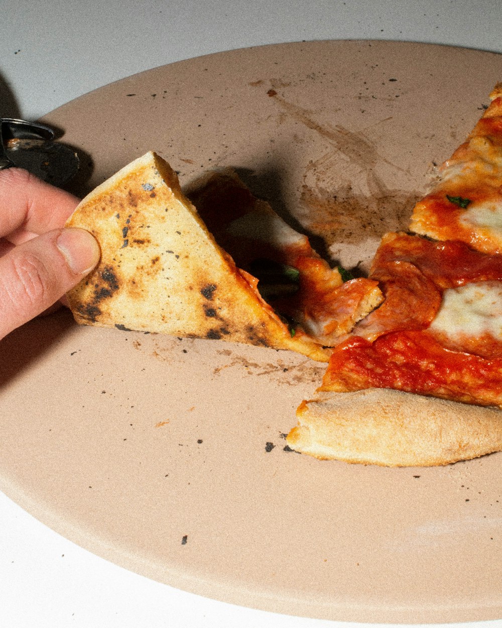 a hand is picking up a slice of pizza from a plate