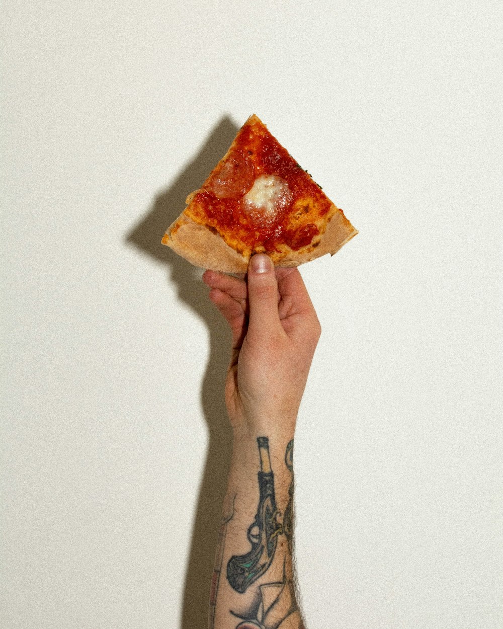 a hand holding up a slice of pizza