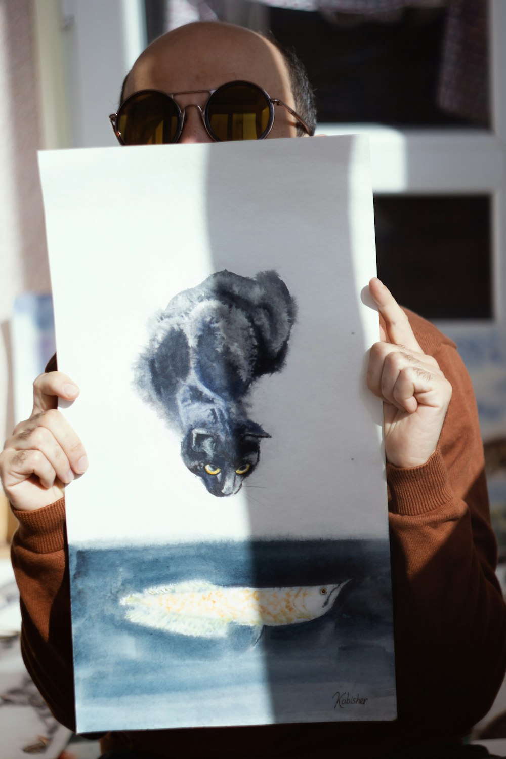 a man holding up a picture of a cat