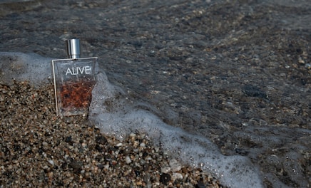 Ocean perfume bottle beside a gentle wave, evoking fresh masculine energy.