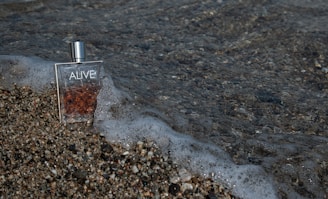 Ocean perfume bottle beside a gentle wave, evoking fresh masculine energy.