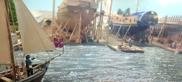 Engineer working on a ship model with technical drawings in the background.