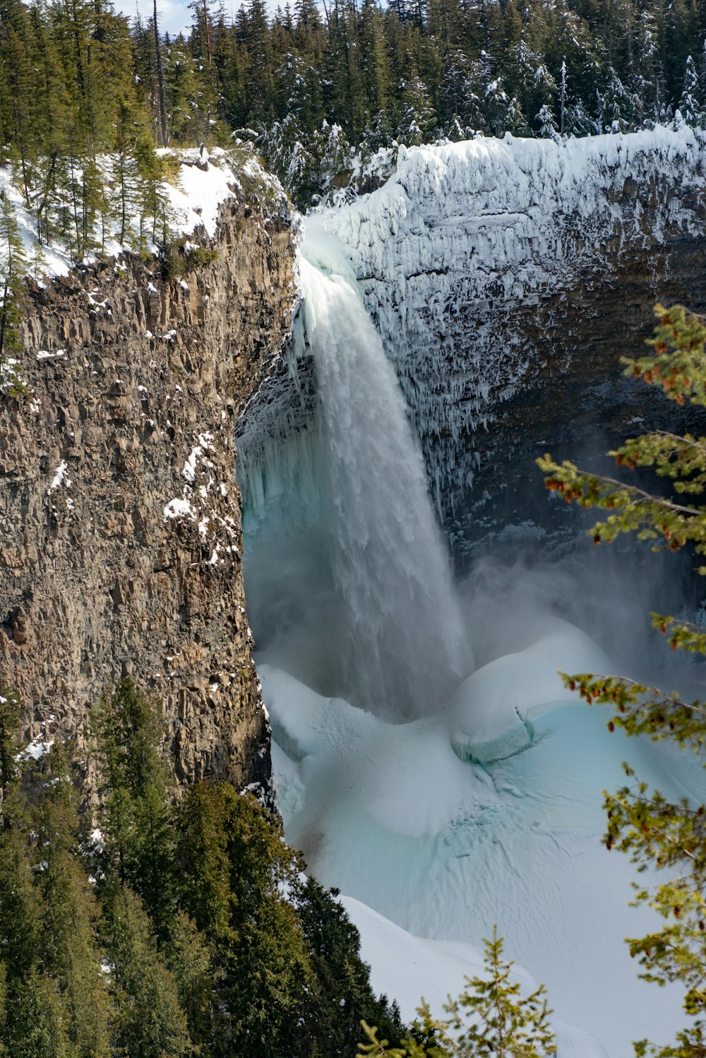 a large waterfall with snow on the ground