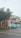 A pastel-colored building features a sign for Archie's of Siesta Key and appears to house a massage therapy business. A light blue Mini Cooper is parked in front of the building. The scene includes palm trees and a wet road, suggesting recent rain.