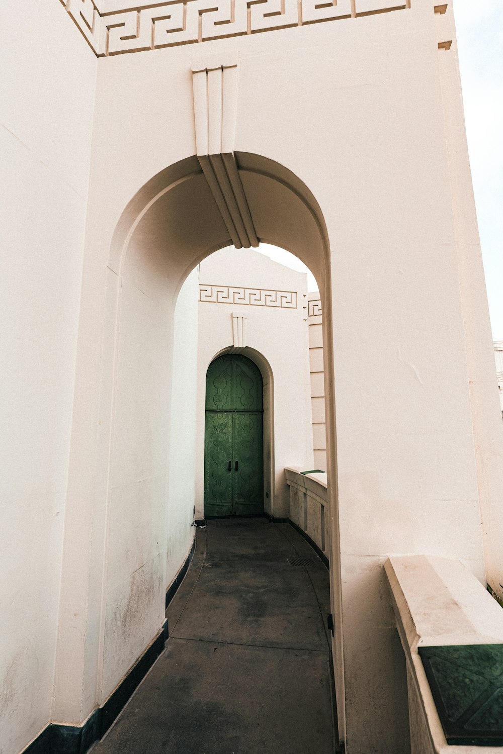 a white building with a green door and a white arch