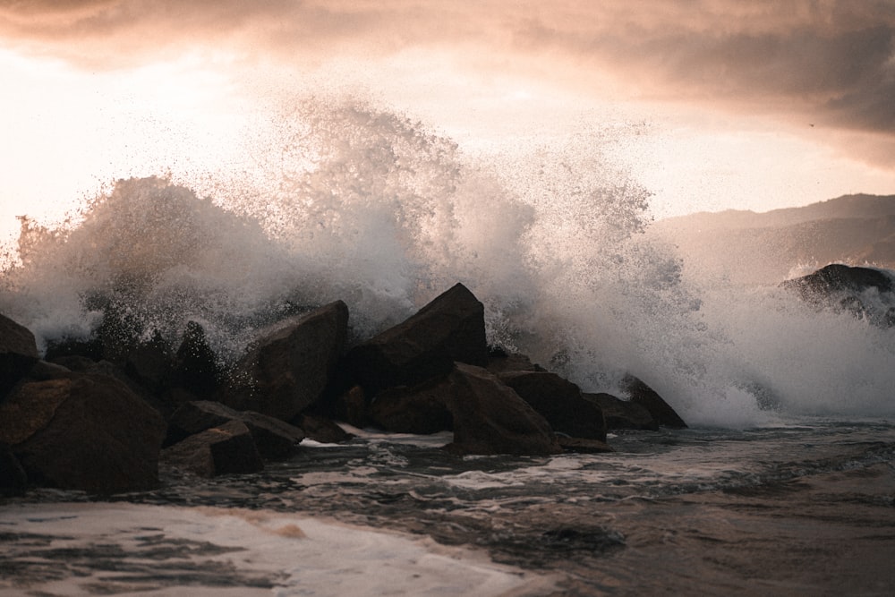 Une grosse vague s’écrase sur des rochers sur une plage