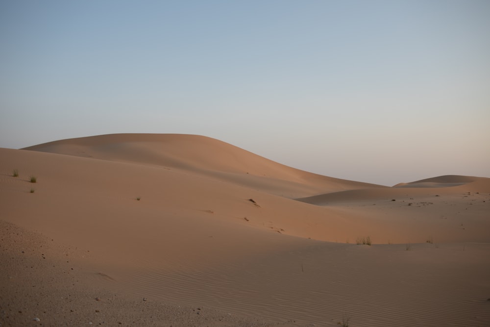 a desert landscape with sand dunes and a blue sky