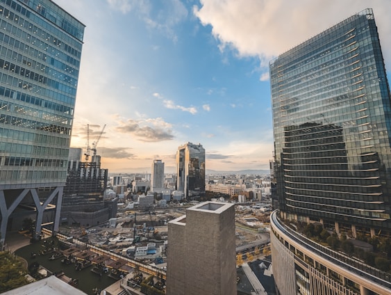 A vibrant cityscape showing new buildings under construction alongside available empty plots bathed in warm sunlight.