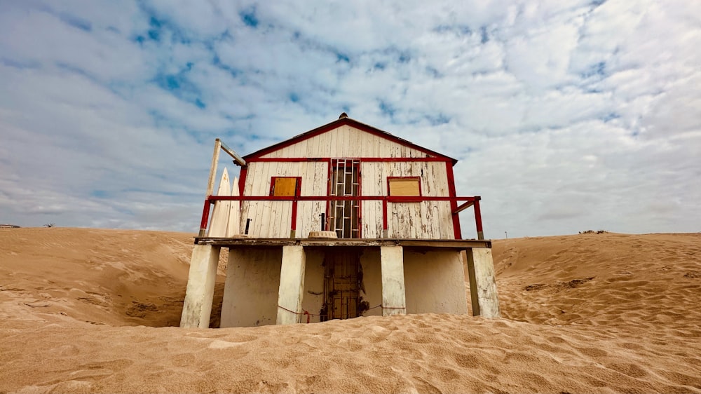 a red and white house sitting on top of a sandy beach