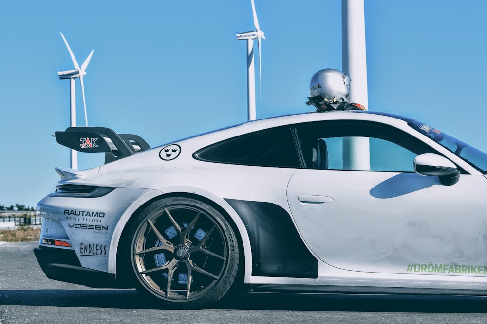 a white sports car parked in front of wind turbines