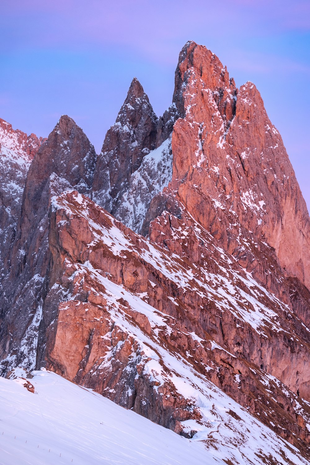 a snow covered mountain with a few skiers on it