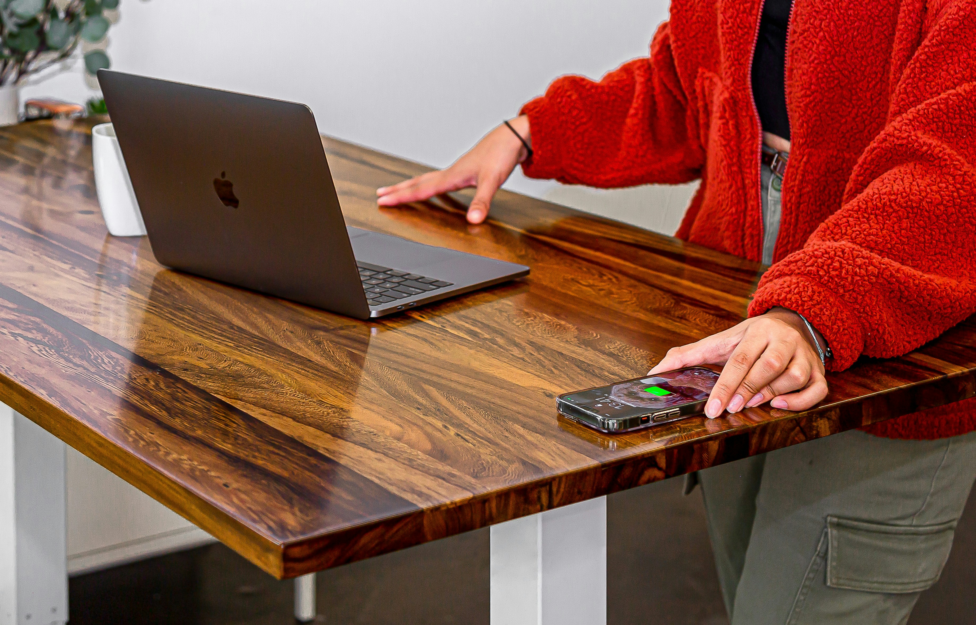 a woman standing at a table with a laptop and cell phone