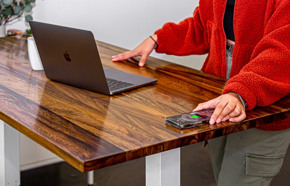 a woman standing at a table with a laptop and cell phone