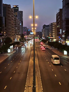 Bustling city street at dusk with glowing lights and people immersed in vibrant urban life.
