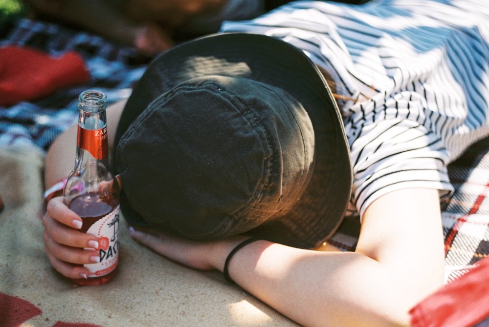a person laying on a blanket with a bottle of beer