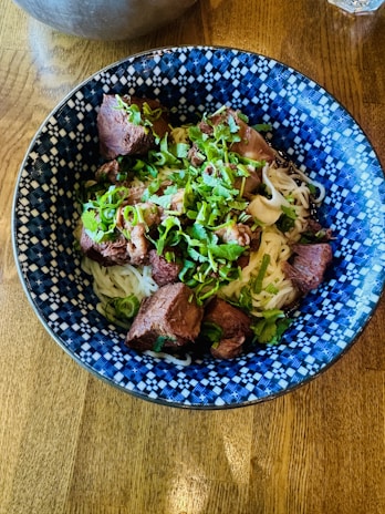 A vibrant bowl of nihari simmering with rich spices and tender meat, garnished with fresh coriander.