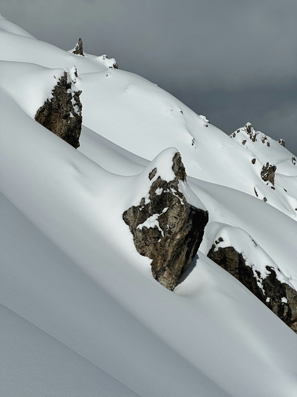 a mountain covered in snow with rocks sticking out of it