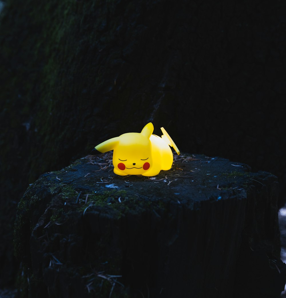 a pikachu figurine sitting on top of a tree stump