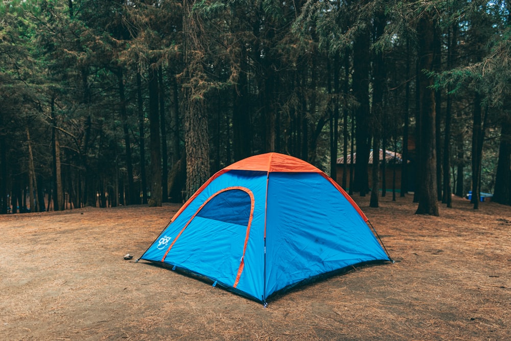 une tente bleue et orange assise au milieu d’une forêt