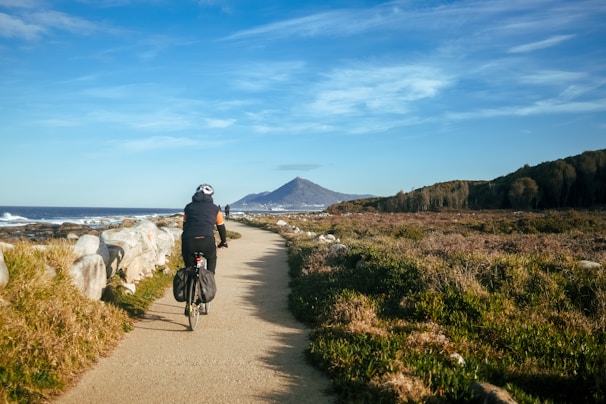 A scenic view of a cyclist riding an electric bike along a coastal path.