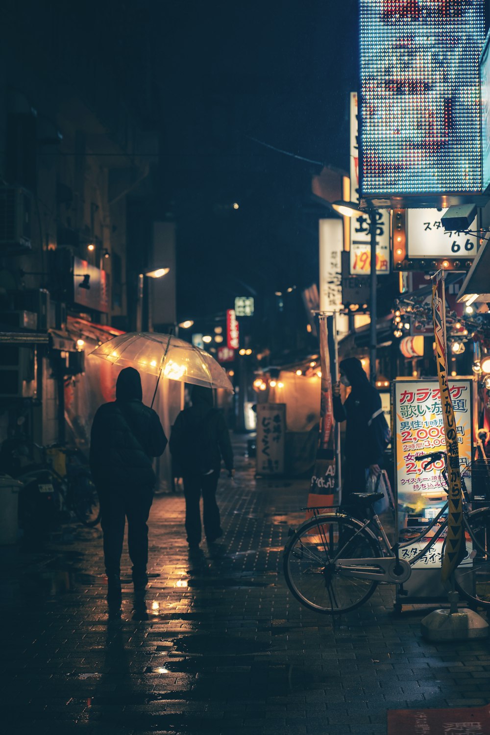 a group of people walking down a street at night