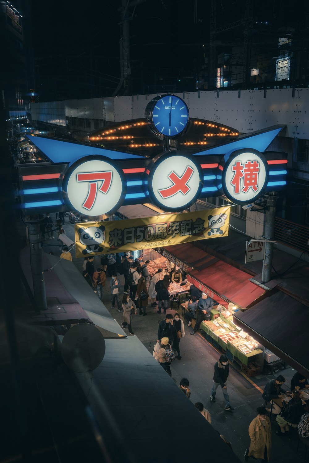 a group of people walking under a neon sign