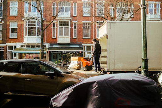 a man standing next to a moving truck on a city street