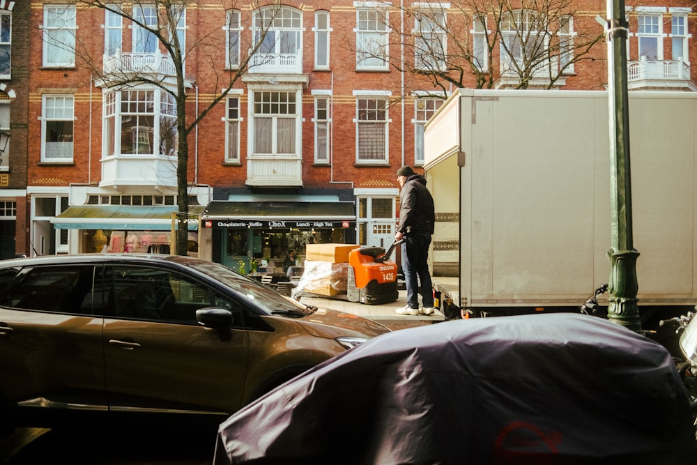 a man standing next to a moving truck on a city street