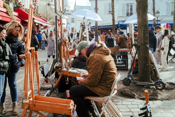 Juan Dona painting live at an outdoor exhibition, surrounded by an engaged audience.