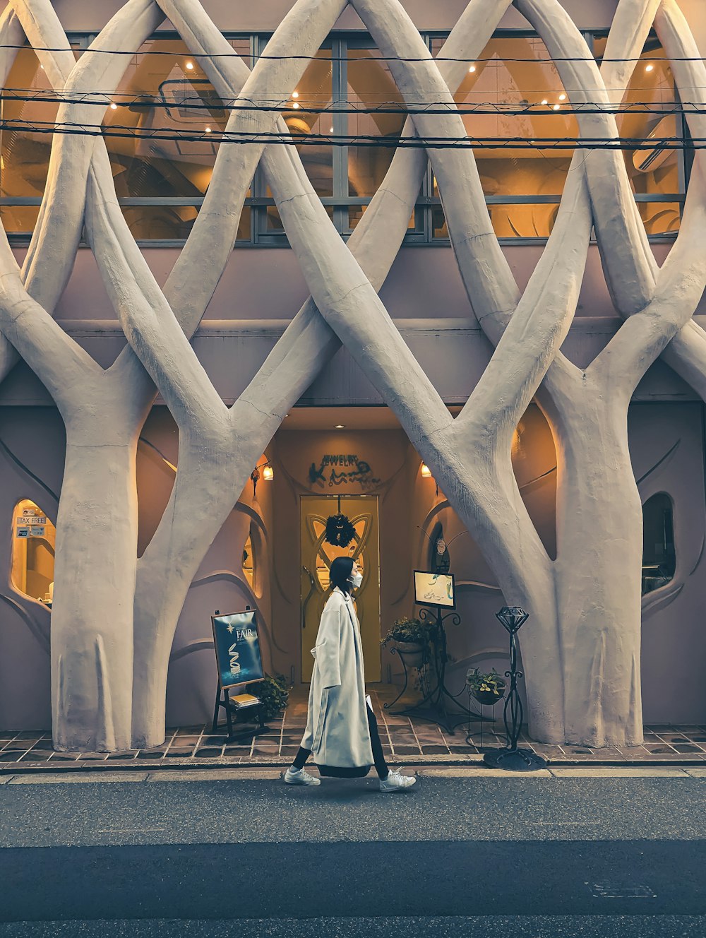 a woman walking down a street past a tall building