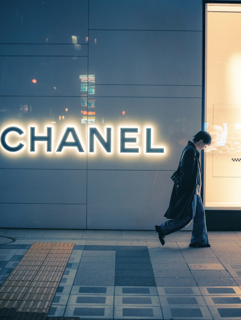 a man walking past a chanel store
