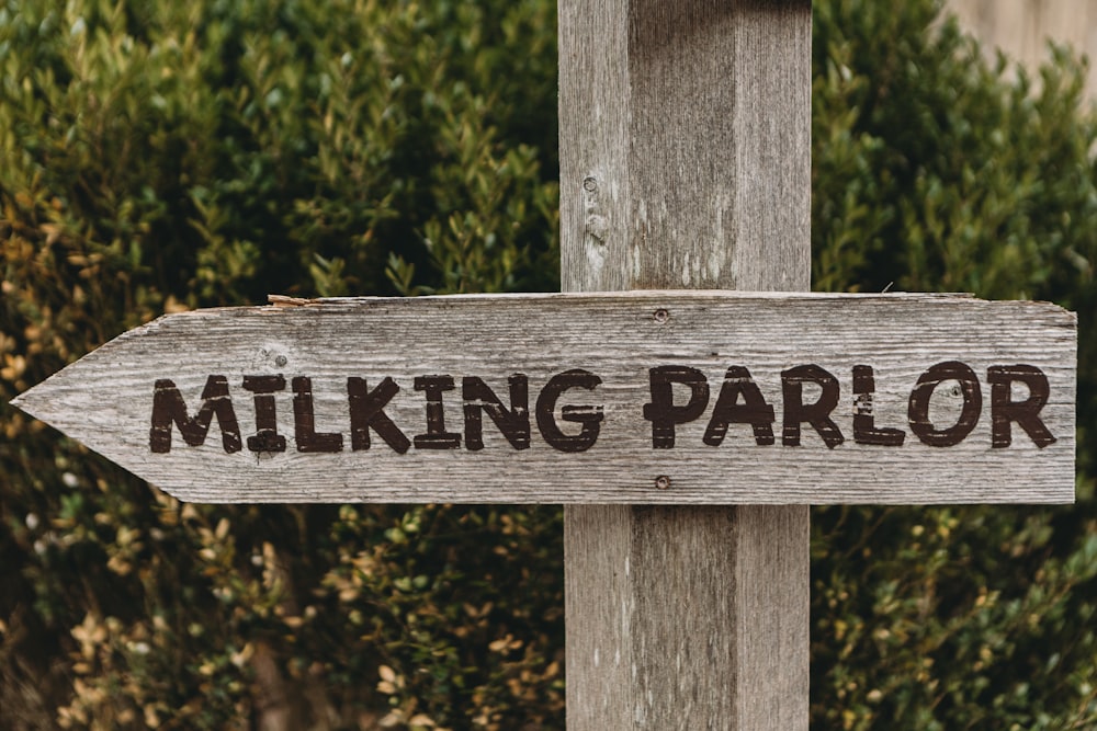 a wooden sign that says milking parlor on it