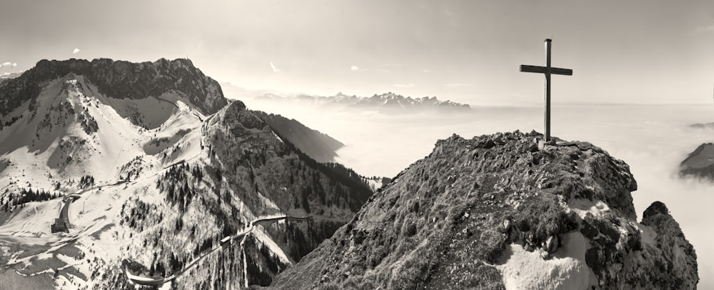 uma foto em preto e branco de uma cruz no topo de uma montanha