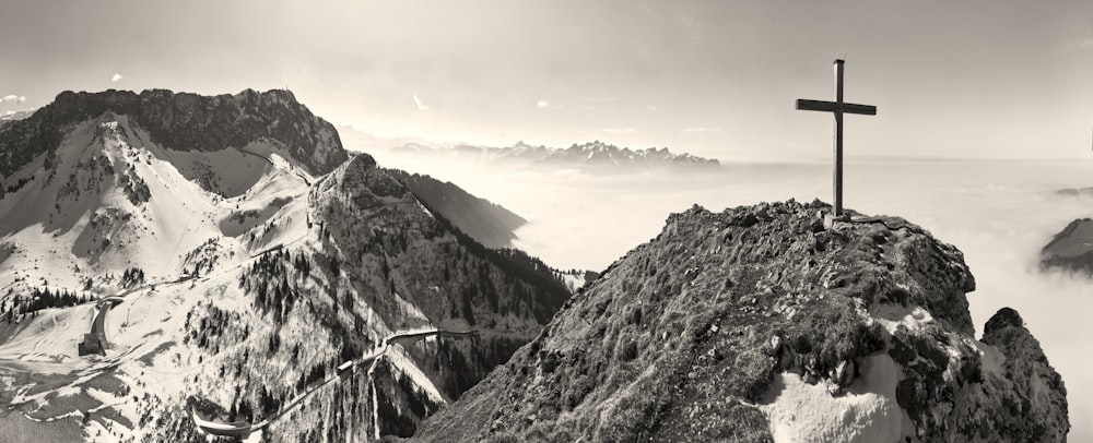 a black and white photo of a cross on top of a mountain