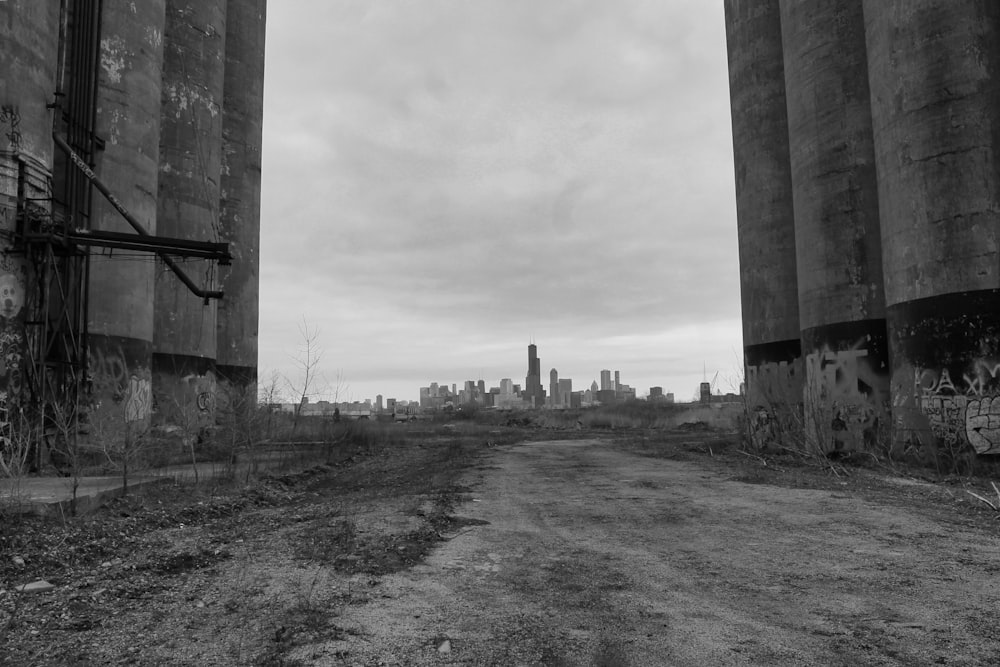 a dirt road between two concrete pillars with graffiti on them