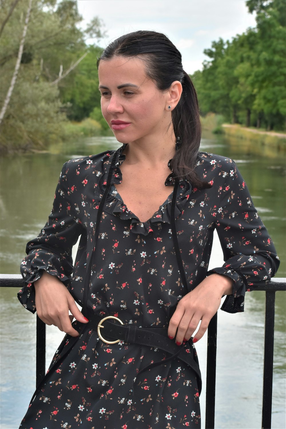 a woman in a black dress standing on a bridge