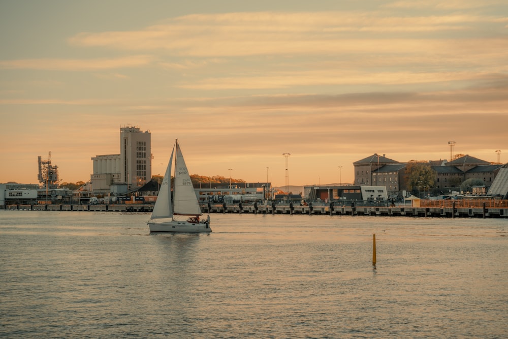 a sailboat in a body of water with a city in the background