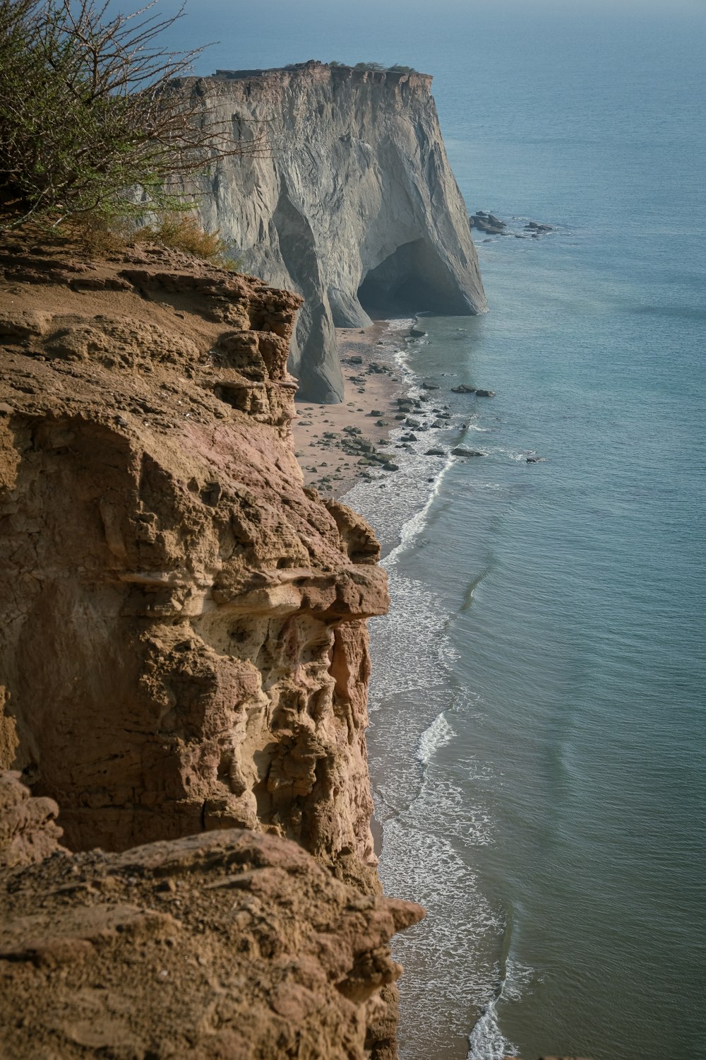 a rocky cliff overlooks the ocean and beach