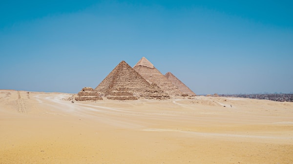 The Great Pyramids of Giza standing against a golden sunset sky