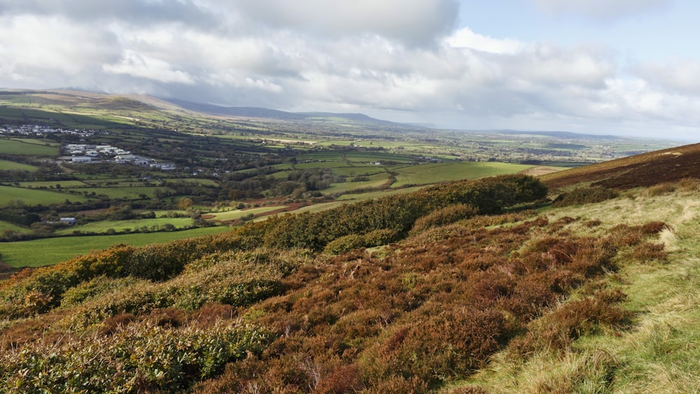 a grassy hill with a view of a town in the distance