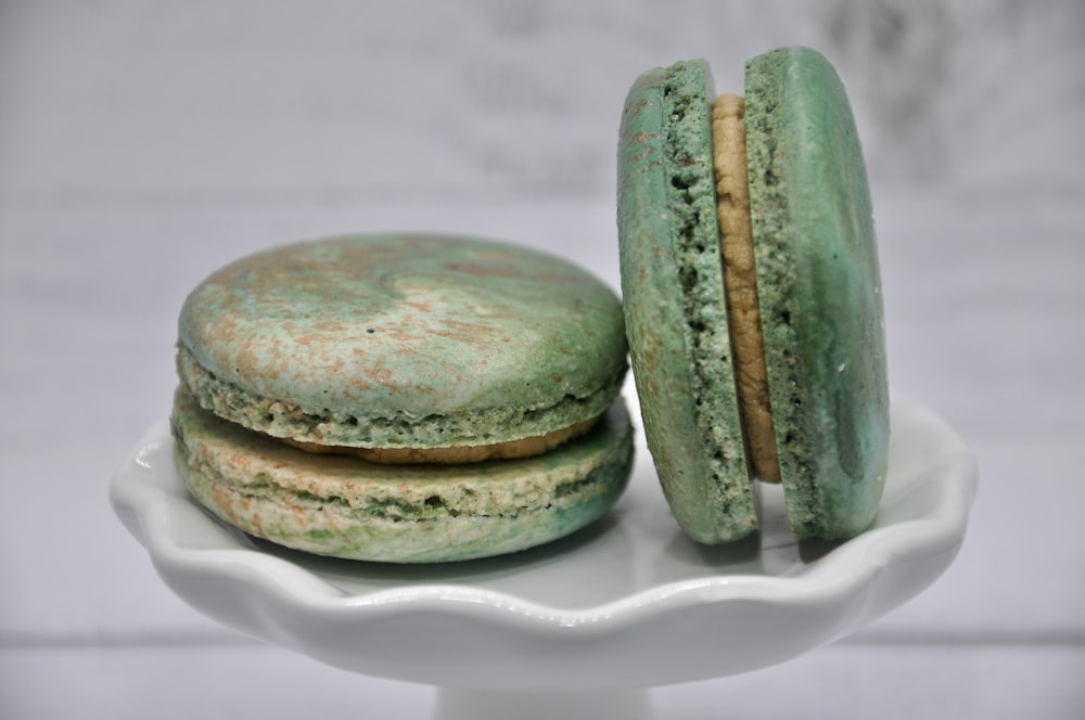 two green macaroons sitting on a white plate