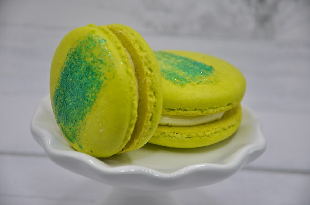 two yellow and green macaroons on a white plate
