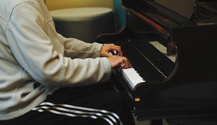 A young girl smiling brightly while playing a grand piano in a warmly lit music room.
