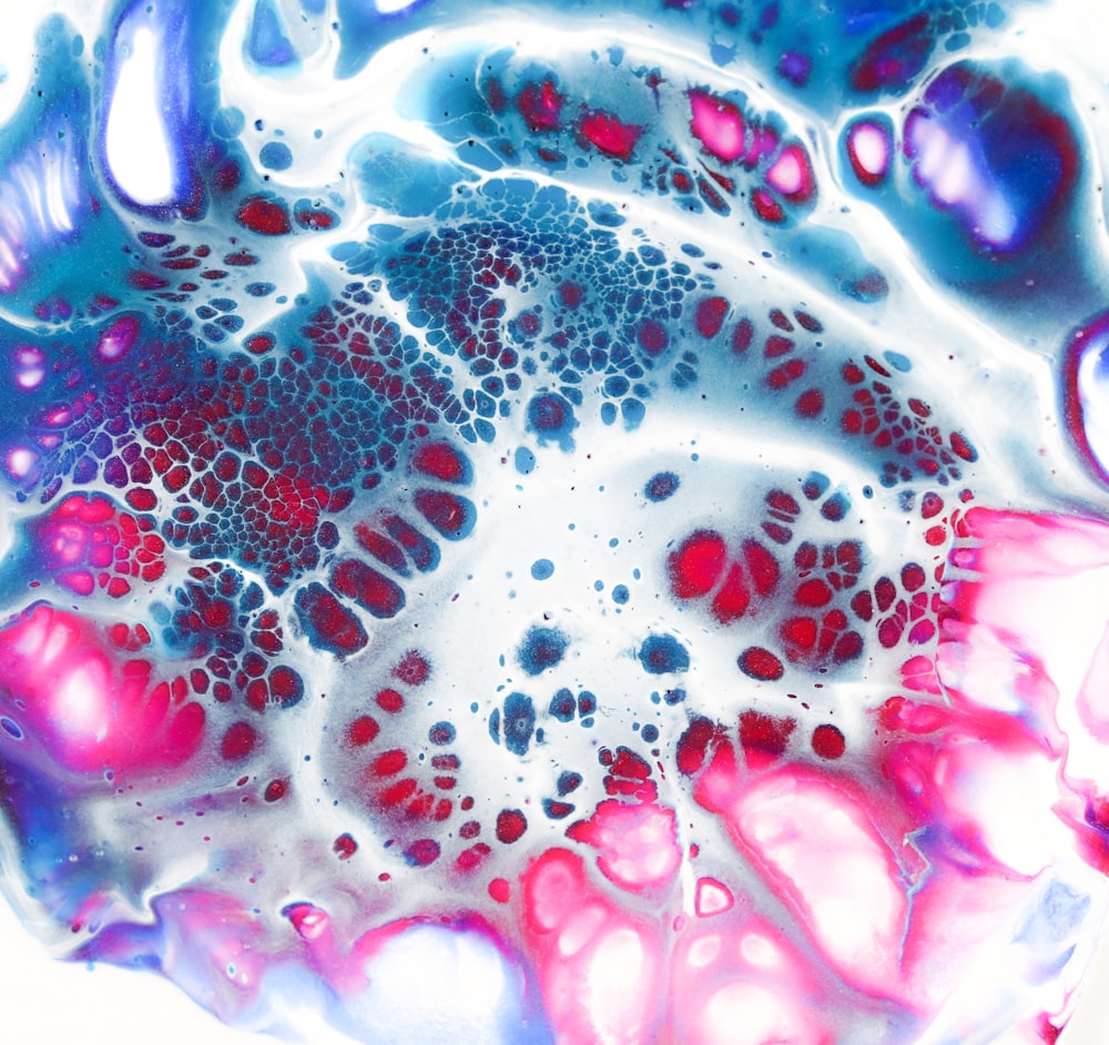 a close up of a liquid filled with blue, pink, and white colors