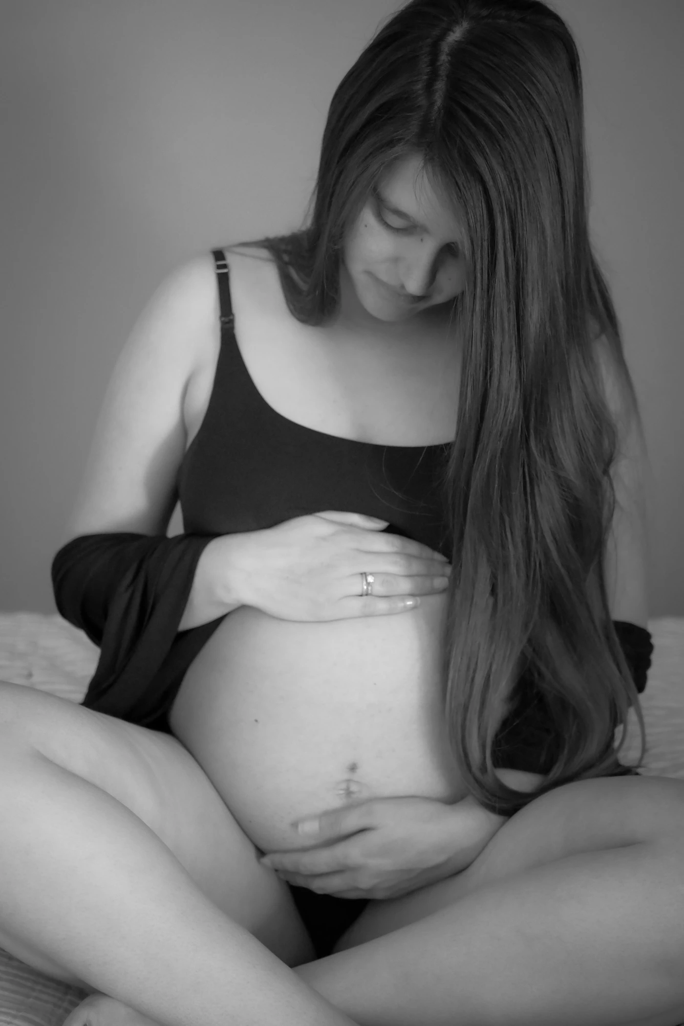Femme enceinte assise sur son lit dans une chambre au style naturel
