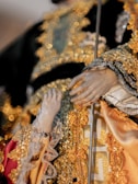 Hands showcasing detailed beadwork and fabric textures on clothing.