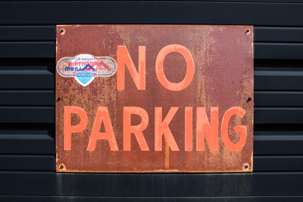 a rusted no parking sign on the side of a building