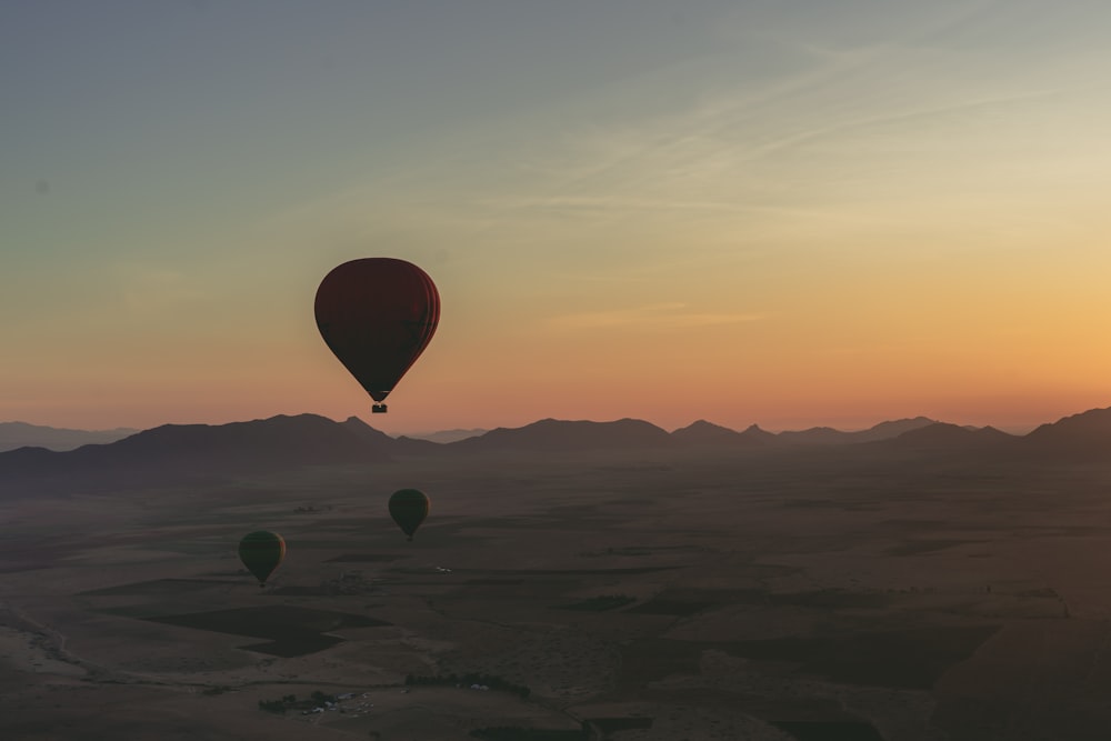 Un grupo de globos aerostáticos volando sobre un desierto